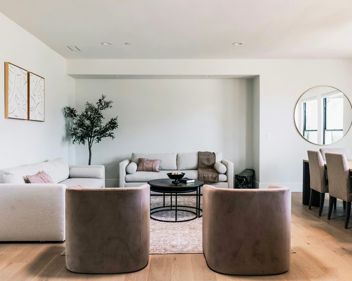 Light-filled living room with cream sofas, warm wood floors and gold accents